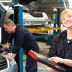 Two mechanics smiling and posing with a clipboard. 