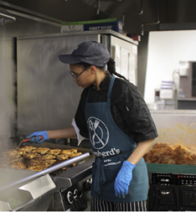 person cooking over stove with apron and gloves on